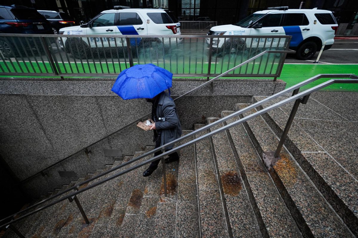 A pedestrian walks down stairs to the CTA Jackson Blue Line station on a rainy day in Chicago, Wednesday, March 5, 2025.