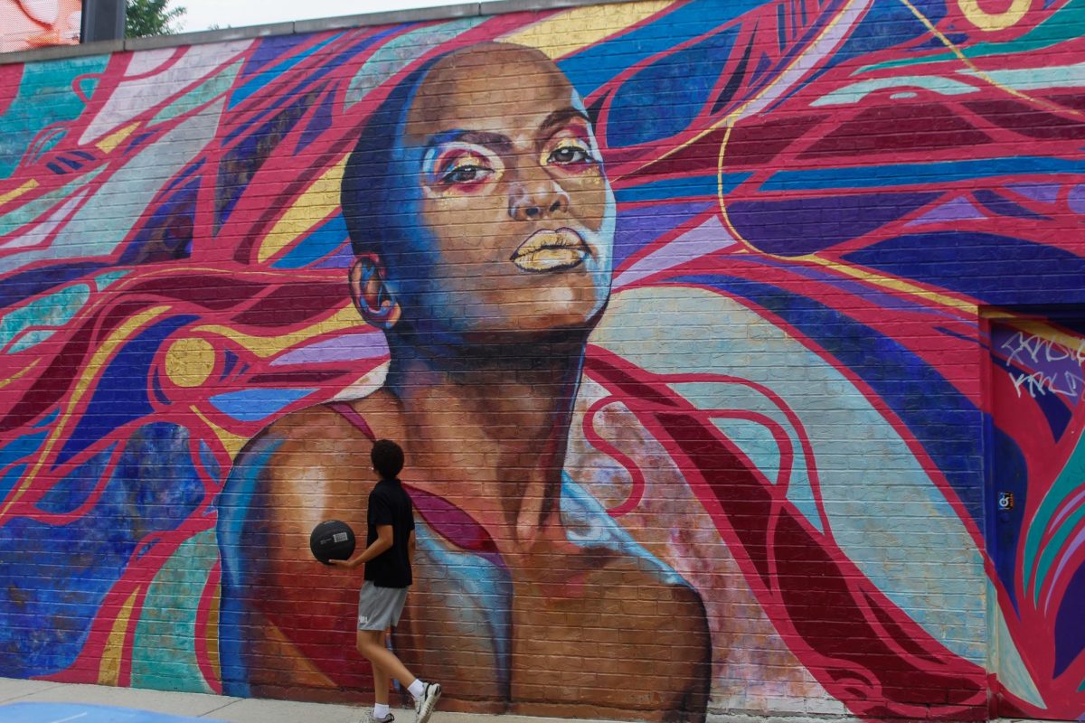 A passerby admires “The Love I Vibrate" mural that honors the LGBTQ and people of color community painted on the side of the Howard Brown Health Clinic in the Boystown neighborhood on Wednesday, June 18, 2025.