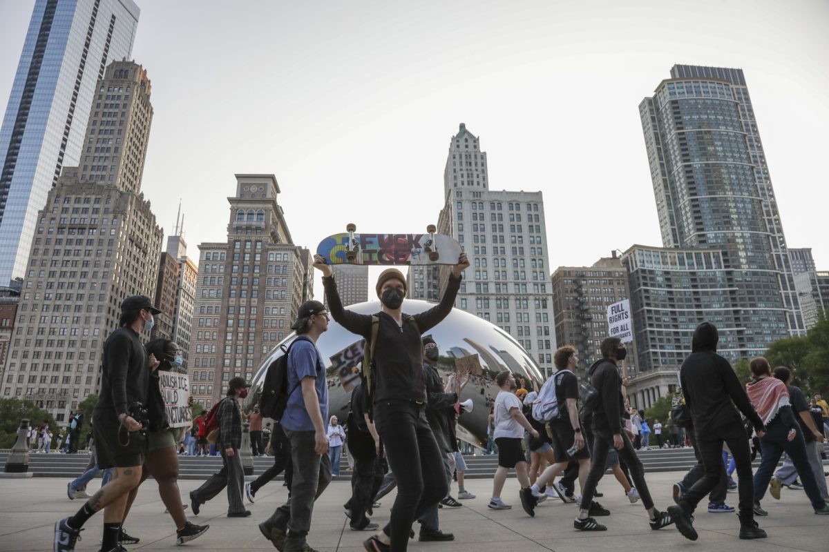 Protester holds a skateboard with a sign reading “Fuck Ice” in front of Cloud Gate on Tuesday, June 10, 2025.