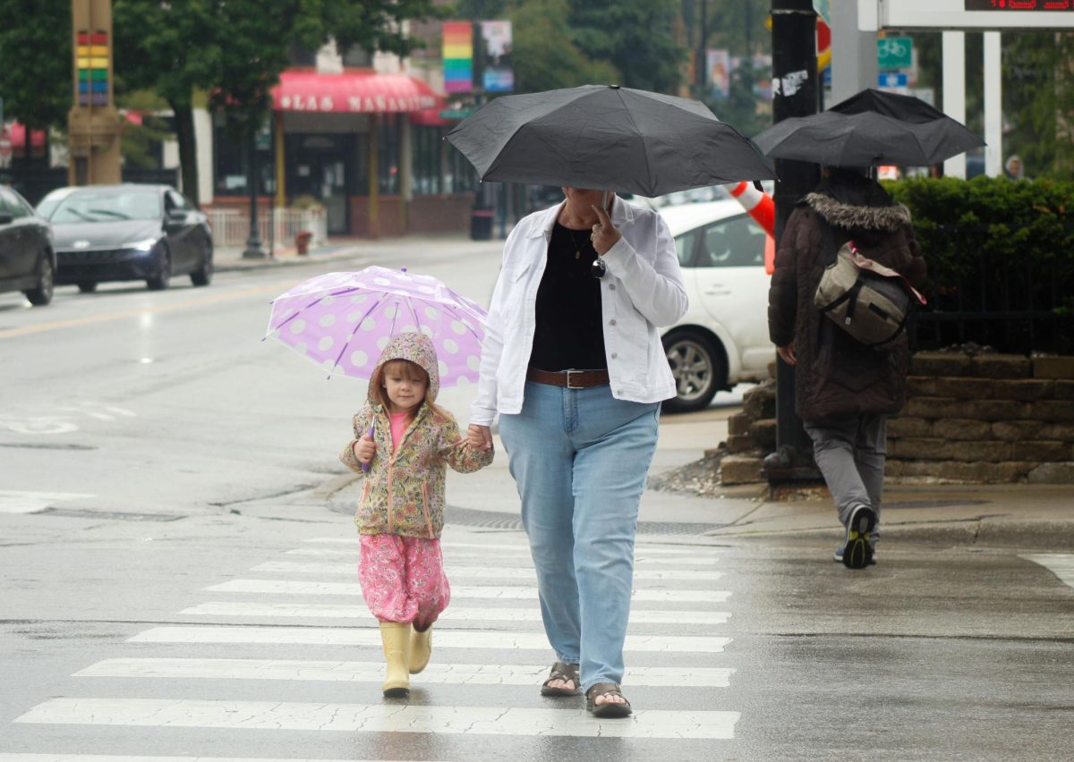 Nancy Holloway walks her granddaughter Iona across the street during a rainy afternoon on Wednesday, June 4, 2025.