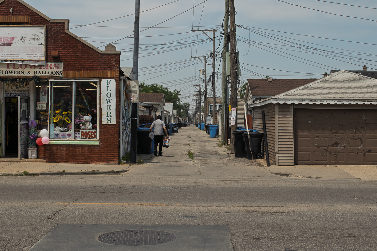 A man throws away trash in an alley near 31st Street and Hamlin Avenue on Friday, June 6, 2025.