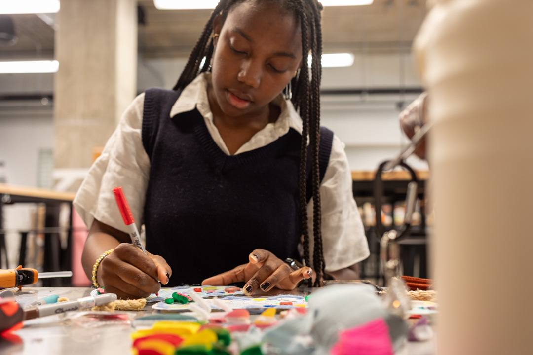 Sy Stewart, a sophomore film and television major, creates invitations with buttons, pipe cleaners and Sharpies for an upcoming Coraline Night she is hosting while working in the Makerspace at the Student Center on Friday, Oct. 17, 2025.