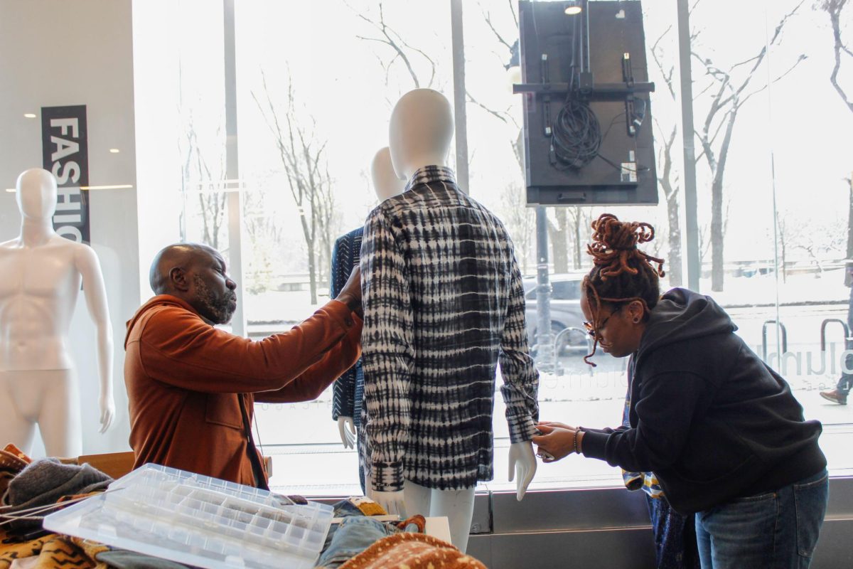 Cyndi Davis, a senior fashion major, helps Maison De Haj dress mannequins with his designs for the "Black Artistry and the Archiv" class's exhibit, displayed at the 618 S. Michigan Ave. building on Tuesday, Dec. 2, 2025.