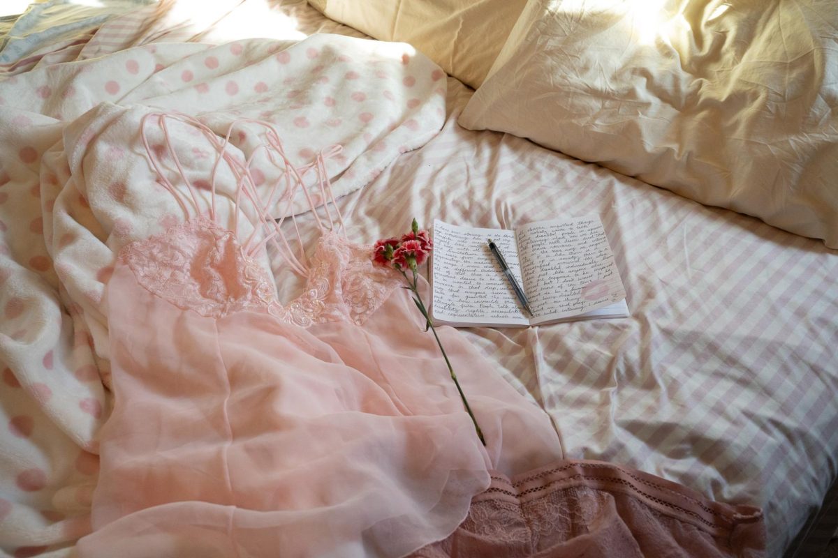 A lace slip dress lies on a bed alongside a journal and flowers on Thursday, Feb. 12, 2026.