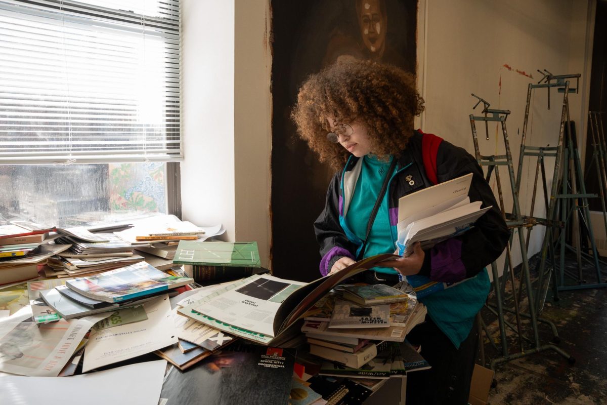 Alivia King, a senior fine arts major, looks through free books in the open studio in the 623 S. Wabash Ave. building on Friday, Feb. 27, 2026.