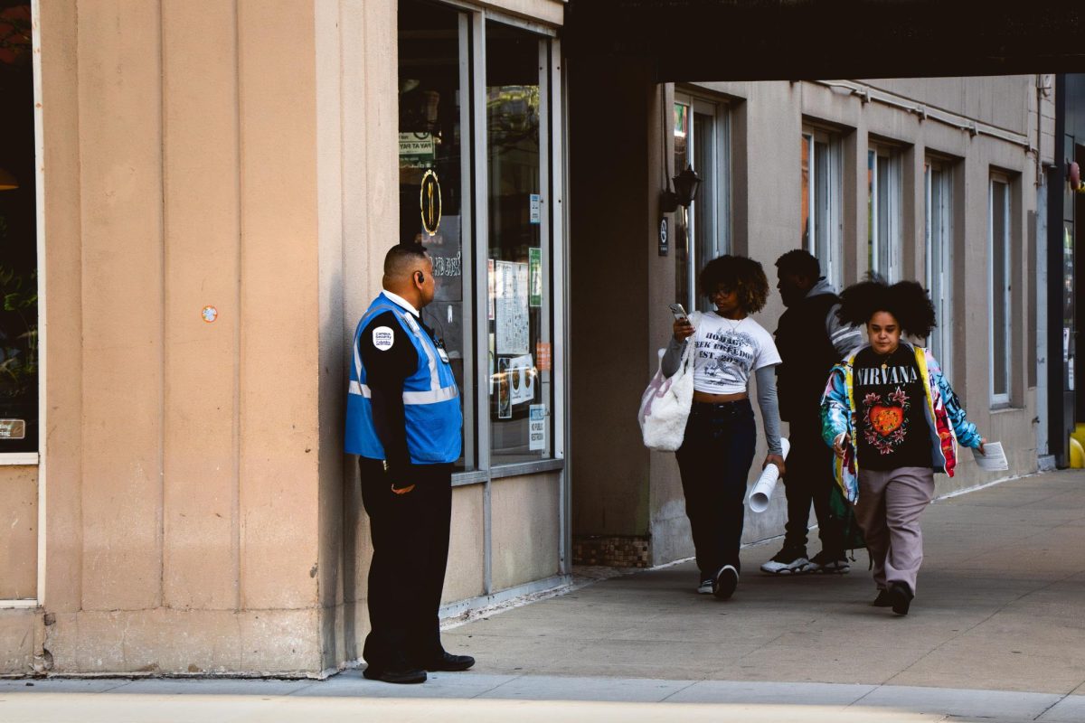 People walk past a campus security guard on the corner of Wabash and Harrison near the 623 S. Wabash building on Wednesday, April 22, 2026.