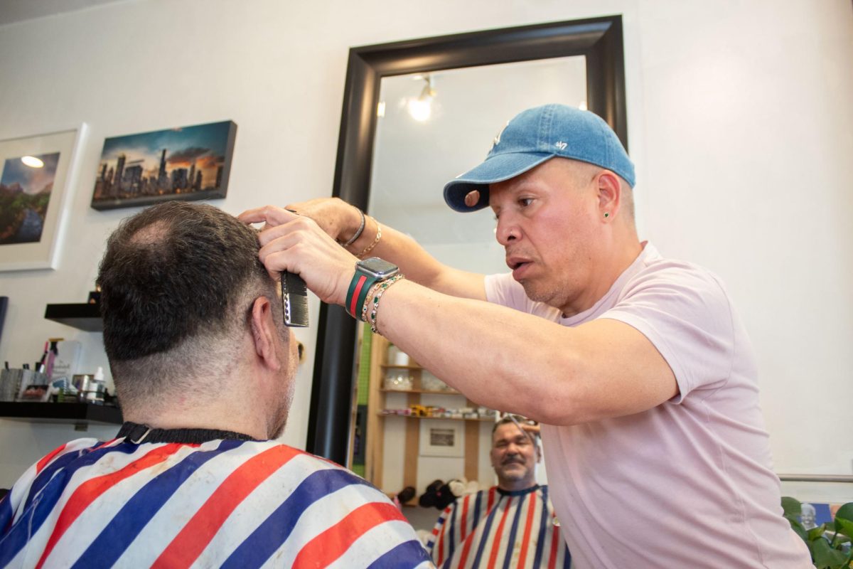 Achilles Nestor gets his annual haircut by Raul Montoya at KP Hair Color in Lake View East on Friday, June 12, 2026. Nestor said that after living overseas every six months, he looks forward to returning to the area and salon every year. This photo is part of the Columbia Chronicle’s “77 Community Areas” project documenting Chicago ahead of America’s 250th birthday.