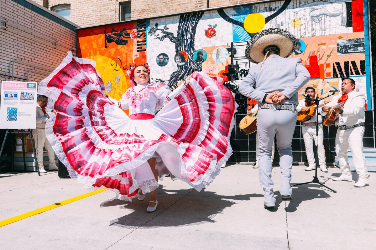 Ballet Folklórico de Chicago dancers twirl in brightly colored dresses while performing a traditional Mexican dance at the Damen Pink Line station in Pilsen on Chicago's Lower West Side on Thursday, June 25, 2026. The performance was part of a celebration marking the Pink Line's 20th anniversary. The line opened June 25, 2006. This photo is part of the Columbia Chronicle’s “77 Community Areas” project, documenting Chicago ahead of America’s 250th birthday.