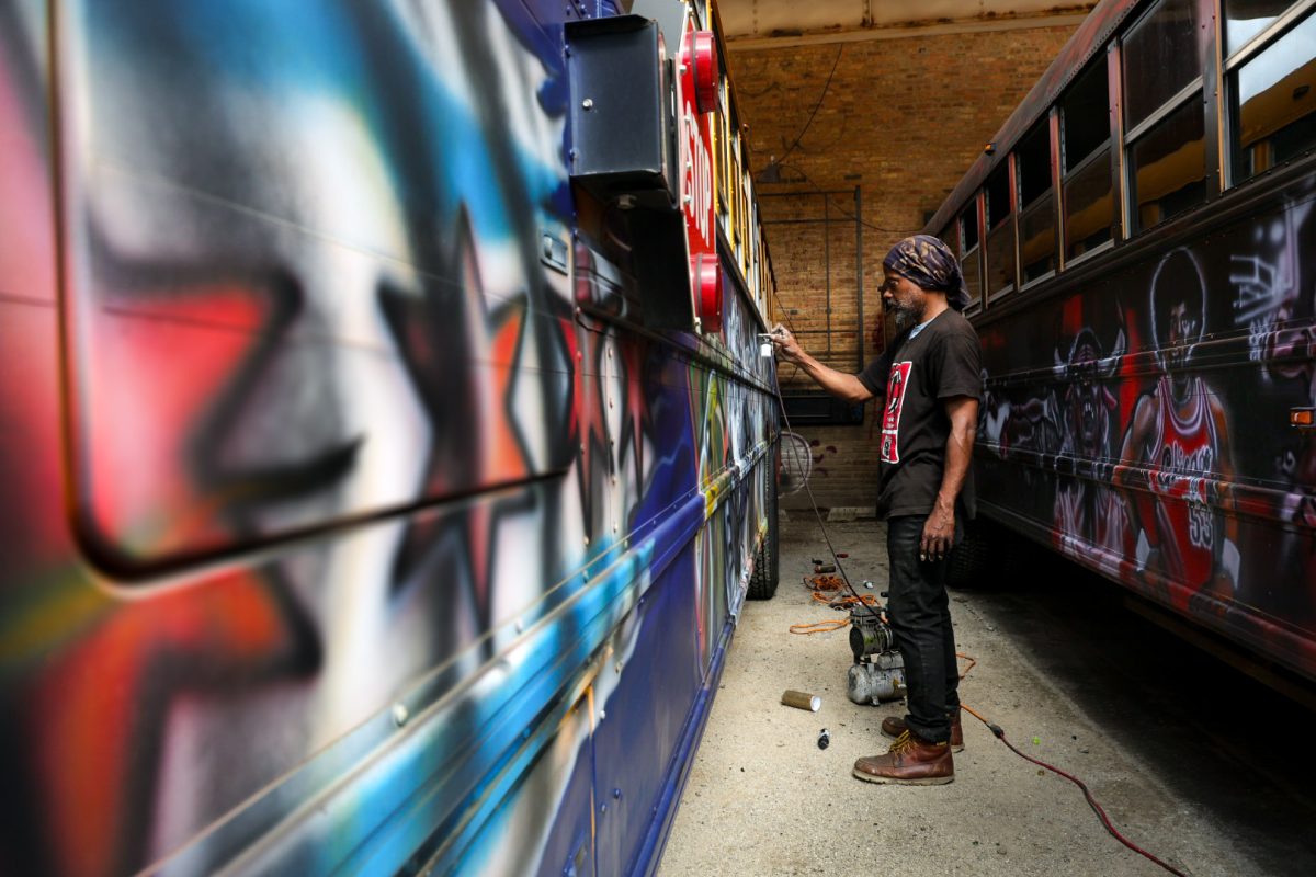 Tee Curtis airbrushes school buses with a Chicagoan theme in Near South Chicago on Tuesday, June 16, 2026. This photo is part of the Columbia Chronicle’s “77 Community Areas” project, documenting Chicago ahead of America’s 250th birthday.