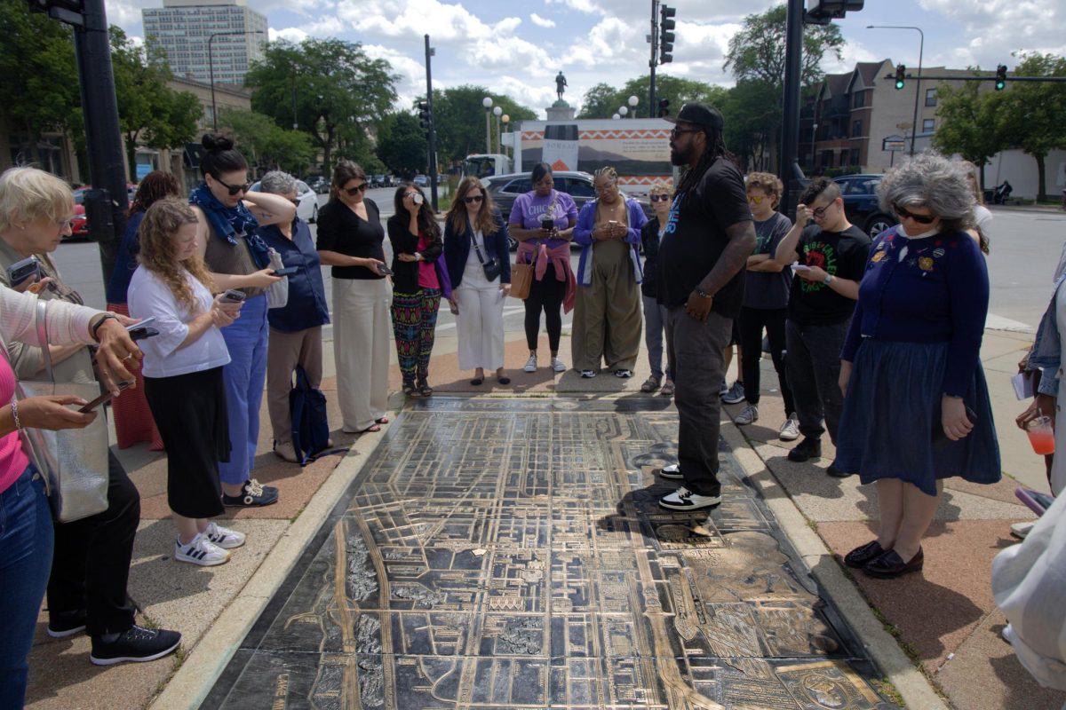 Sherman “Dilla” Thomas stands on a bronze map depicting Chicago’s history of African American roots during a tour of the Bronzeville neighborhood and South Side on Friday, June 26, 2026. This photo is part of the Columbia Chronicle’s “77 Community Areas” project, documenting Chicago ahead of America’s 250th birthday.