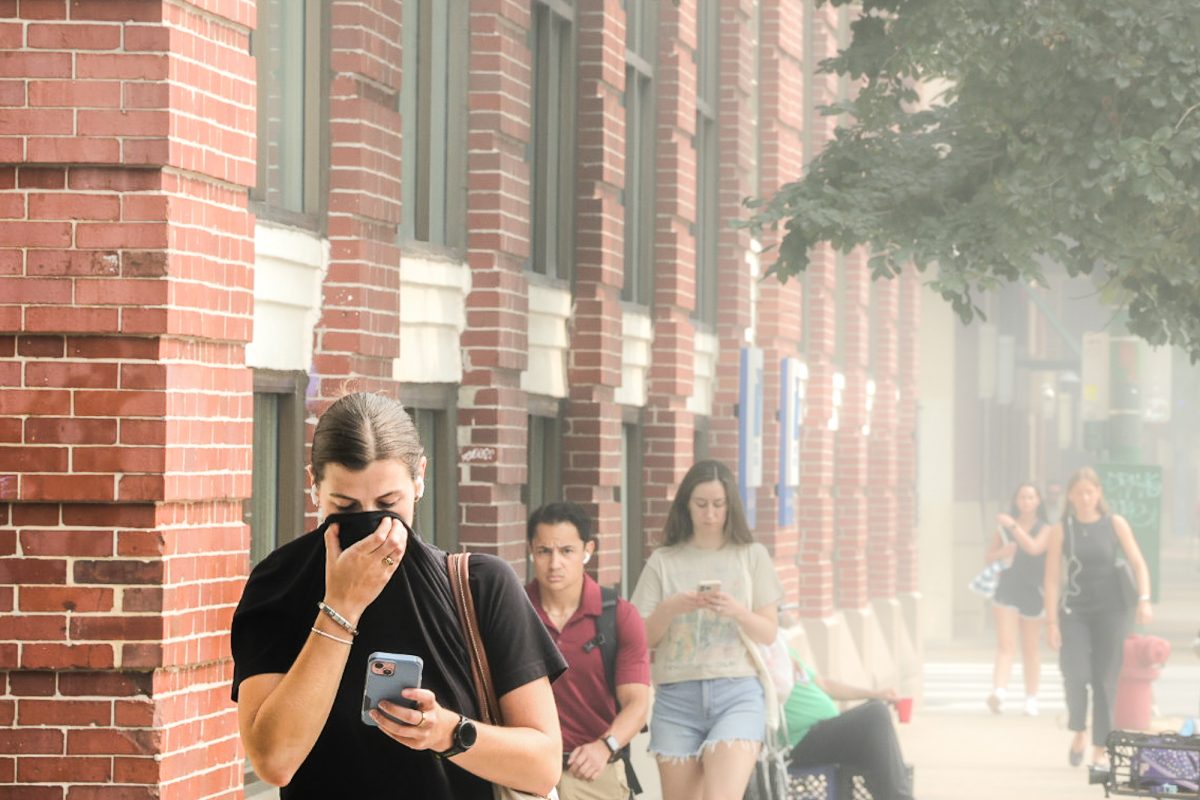 A woman holds her shirt over her mouth in the Lincoln Park neighborhood due to Chicago's hazardous air quality on Thursday, July 16, 2026. A citywide alert was sent out after the air quality index exceeded 400, which is attributed to Canadian wildfires. This photo is part of the Columbia Chronicle's "77 Community Areas" project, documenting Chicago in celebration of America's 250th birthday.