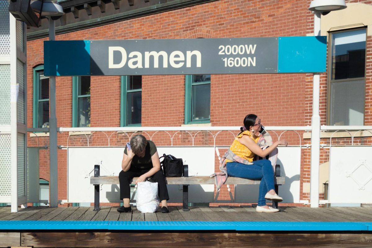 Two commuters wait on the platform at the Damen Blue Line station in the Wicker Park neighborhood on Wednesday, July 8, 2026. This photo is part of the Columbia Chronicle’s “77 Community Areas” project, documenting Chicago in celebration of America’s 250th birthday.