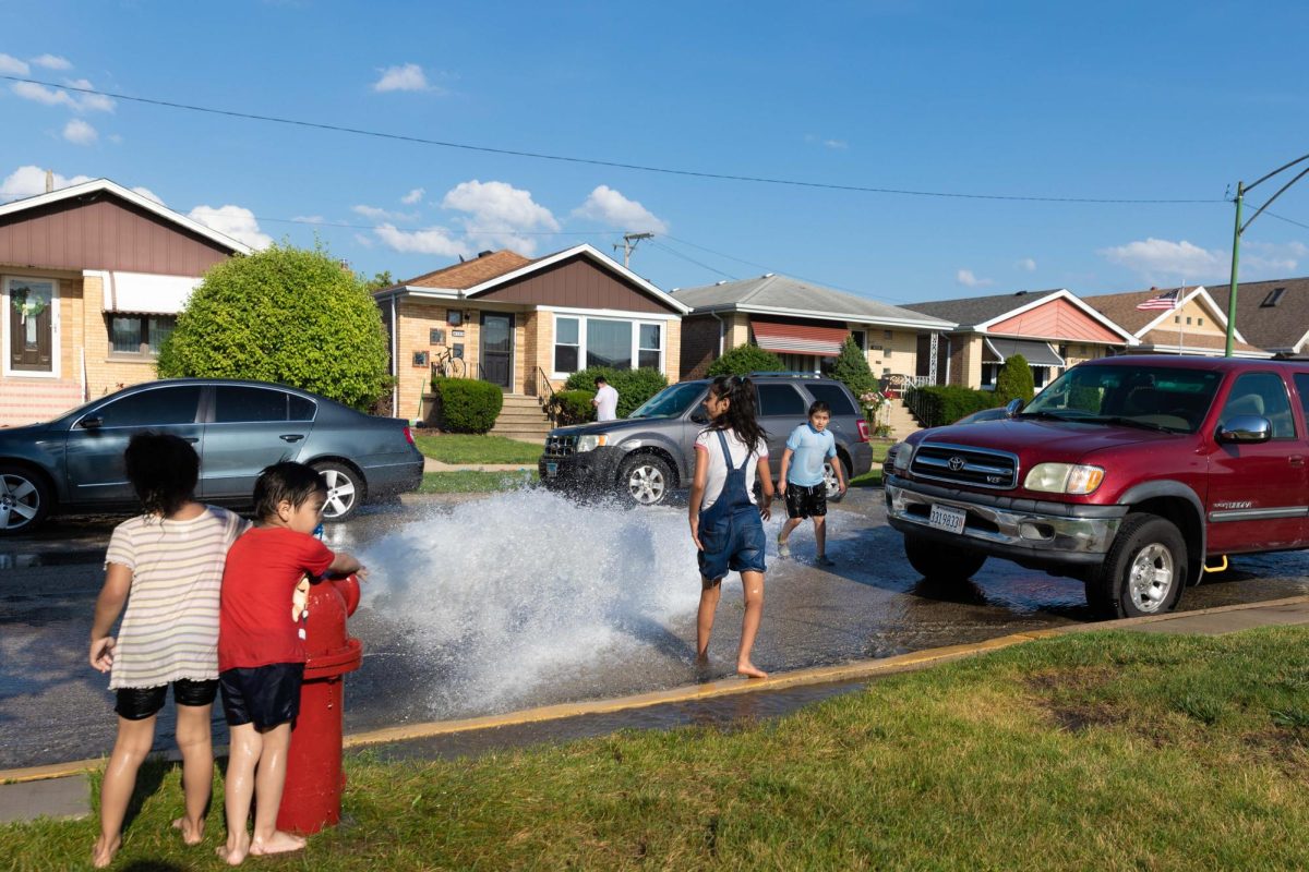 Children run through a spray of water from a fire hydrant in the Archer Heights neighborhood in Chicago on Thursday, July 2, 2026, during a summer heat wave. This photo is part of the Columbia Chronicle’s “77 Community Areas” project, documenting Chicago ahead of America’s 250th birthday.