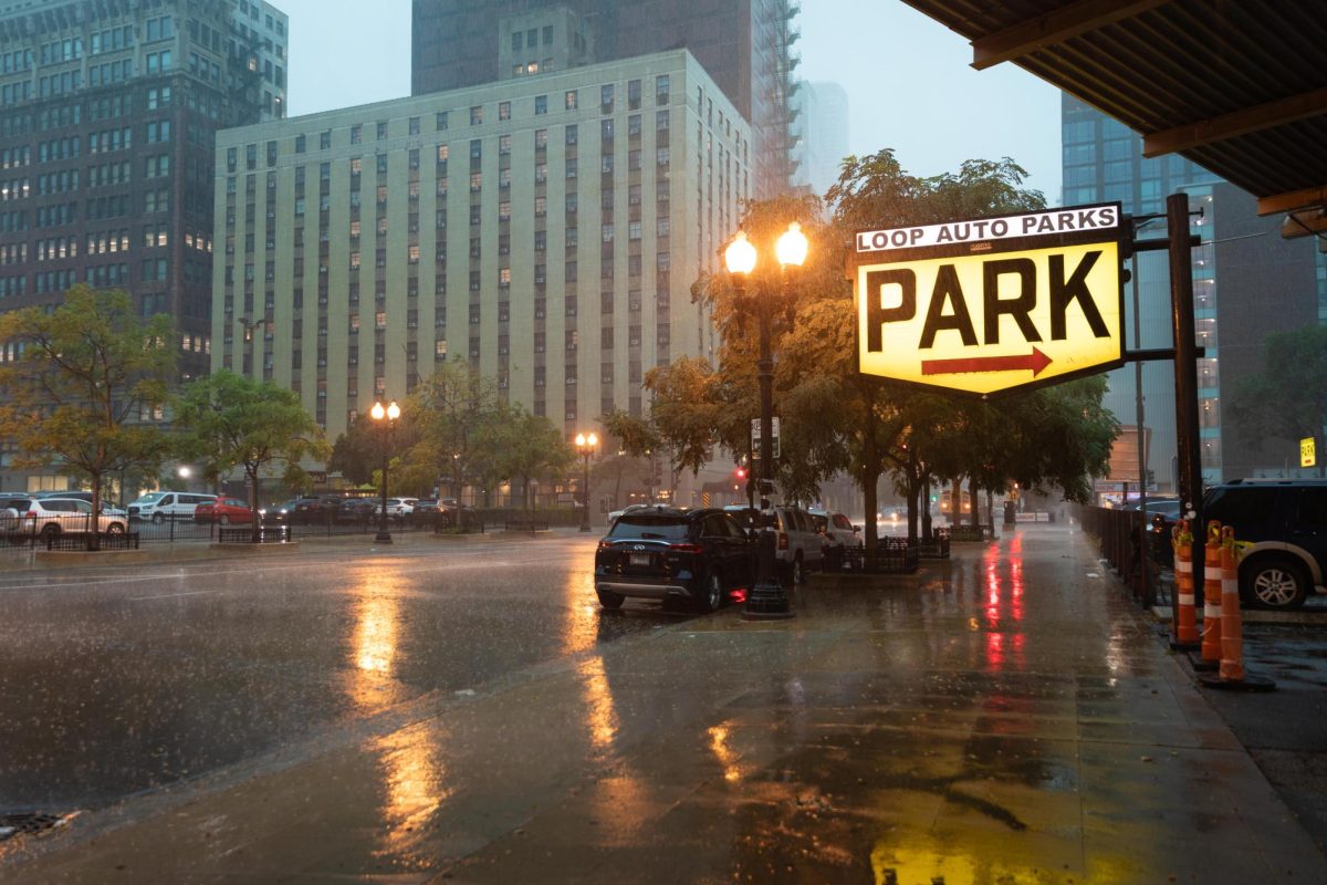Rain reflects off wet asphalt near a Loop Auto Parks sign as a sudden downpour moves through the area on Tuesday, Aug. 11, 2026.