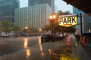 Rain reflects off wet asphalt near a Loop Auto Parks sign as a sudden downpour moves through the area on Tuesday, Aug. 11, 2026.