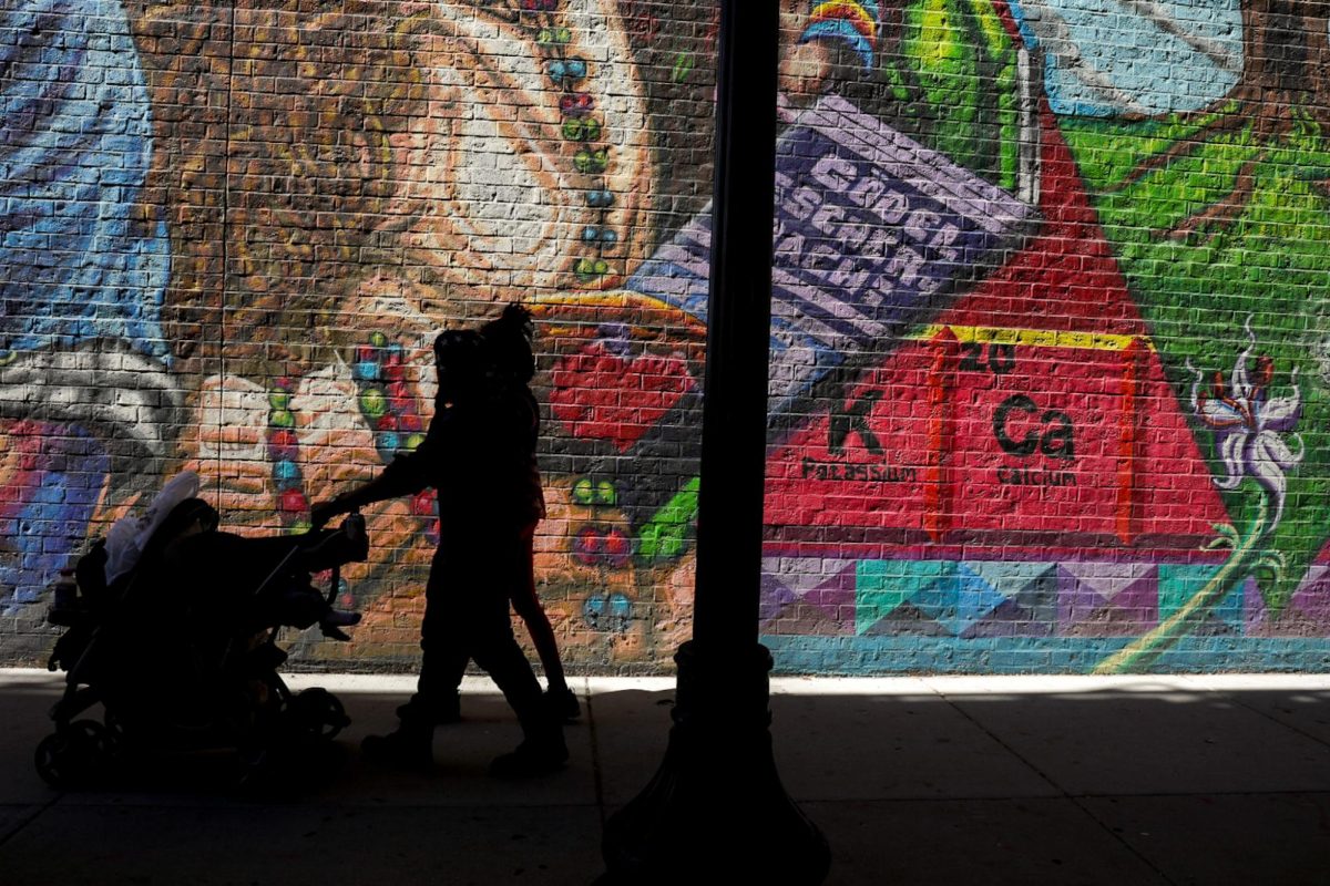 While pushing a stroller, a couple passes by “Supreme Mathematics,” a vibrantly-painted mural by Chicago-based street artist Rahmaan Statik in the Woodlawn neighborhood on June 12, 2026. This photo is part of the Columbia Chronicle's "77 Community Areas" project, documenting Chicago in celebration of America's 250th