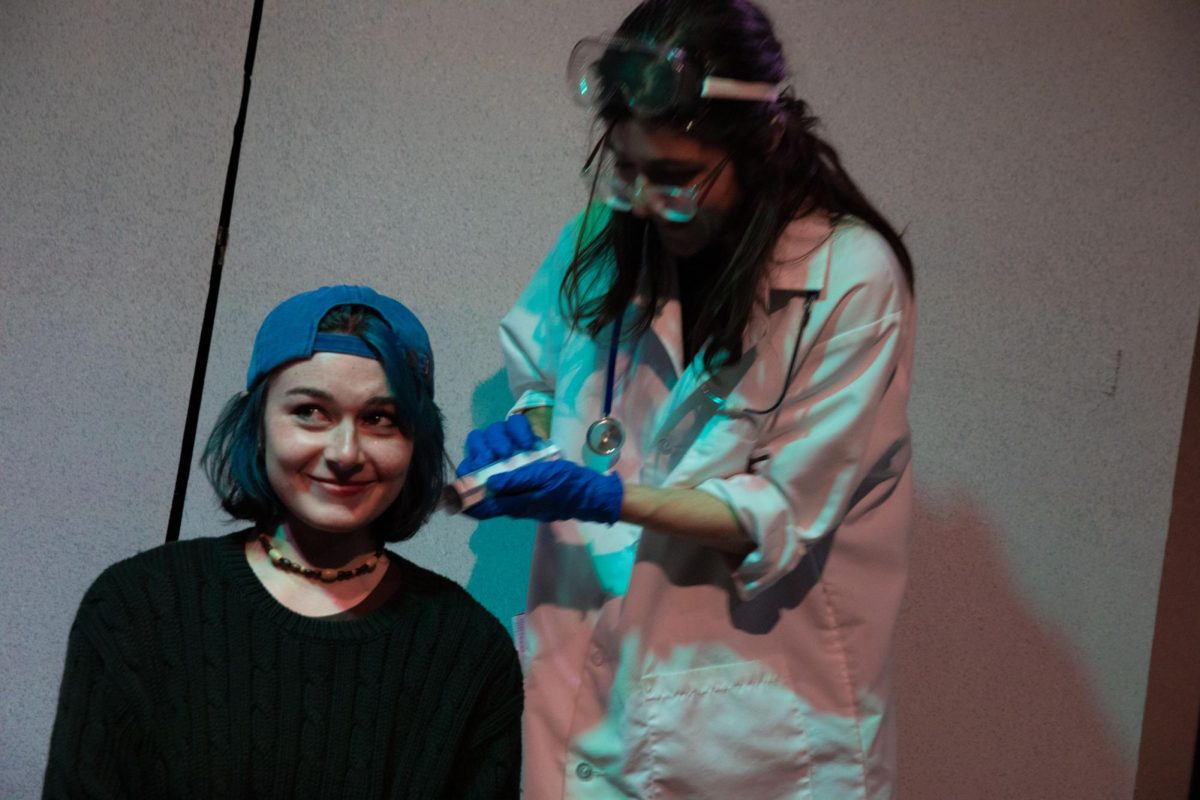 Caleb Immel, a first-year theatre arts production and practice major playing “Dr. Murder,” examines participant Sionainn Davis, a junior theatre design and technology major, during the “Dr. Murder’s Extraordinary Magical Healing Program” haunted house at the Columbia Theatre building, 72 E. 11th St., on Monday, Oct. 26, 2026.