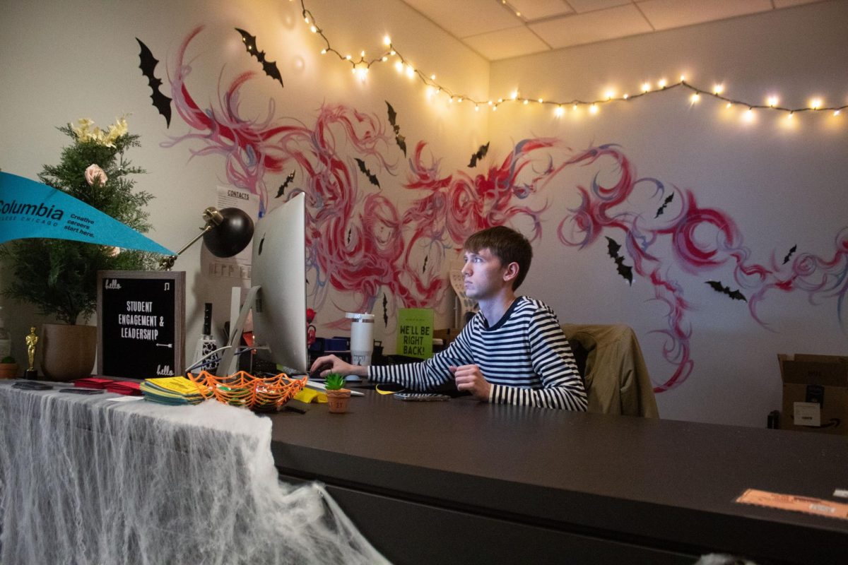 Jack Hewitt, junior musical theatre major and involvement ambassador for the Student Engagement and Leadership Office, works the front desk, decorated for Wicked Week on Wednesday, Oct. 21, 2026.